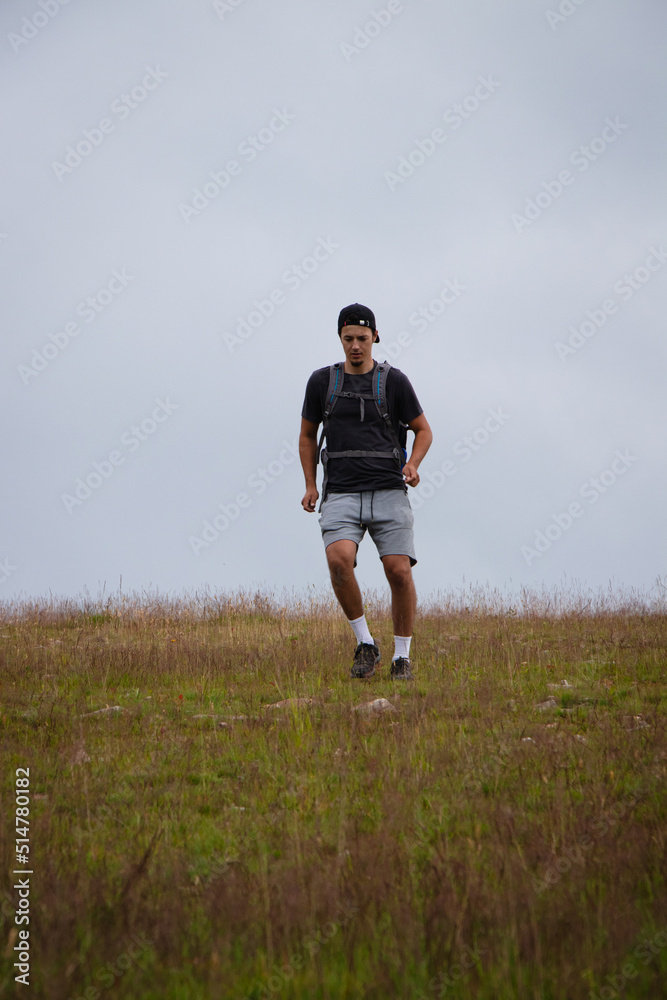 Obraz premium Swarthier type of man is running down a gravel hill, checking his every step to avoid injury. Active athlete runs over challenging terrain to improve fitness, coordination and precision of movement