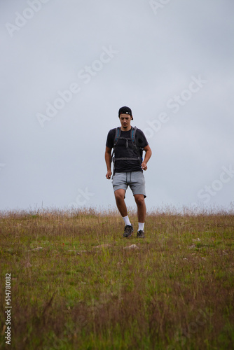 Swarthier type of man is running down a gravel hill, checking his every step to avoid injury. Active athlete runs over challenging terrain to improve fitness, coordination and precision of movement © Fauren
