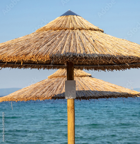 Straw beach umbrella close up. Sunny day at sea. Summer holiday in Greece