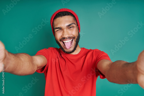 Photos Playful African man stretching out hands while standing against green background