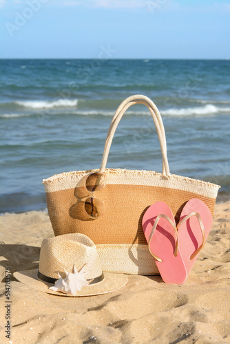 Stylish bag and other beach accessories near sea on sunny day
