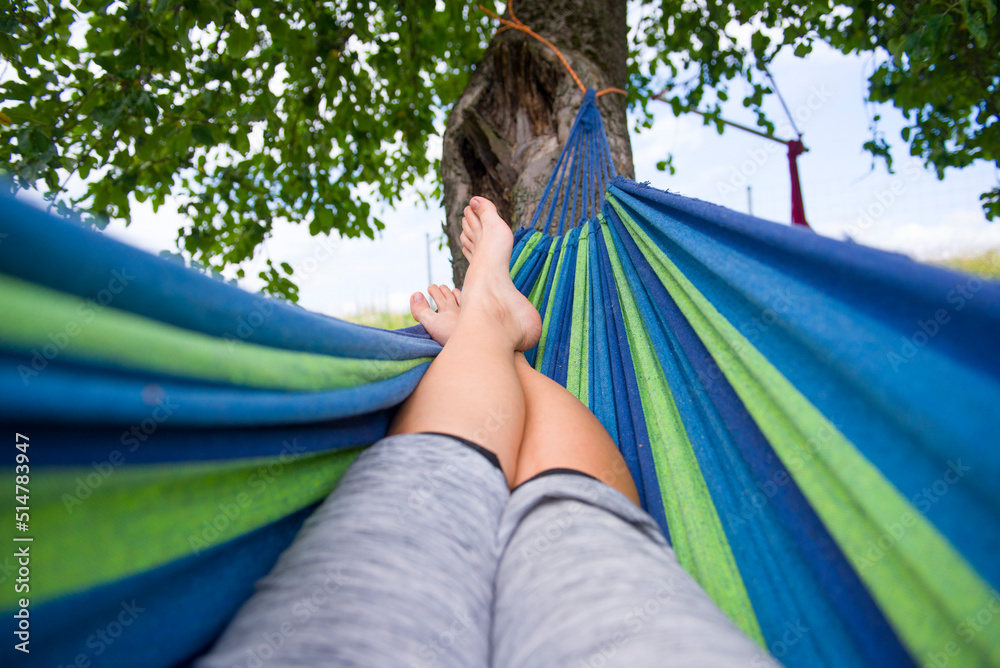 Wypoczynek na hamaku pod drzewem jest dobrym sposobem na relaks w ciepłe dni. - obrazy, fototapety, plakaty 