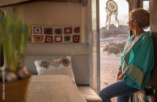 Travel lifestyle and daydreaming people. Woman standing onthe entrance door of her modern camper van motor home enjoying freedom and living off grid. Renting vehicle for holiday vacation journey photo