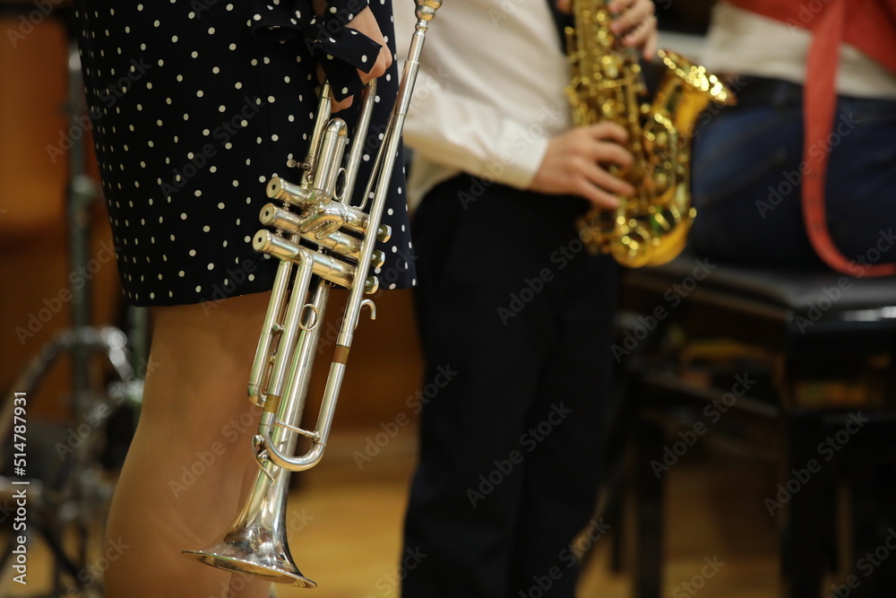 Obraz premium A woman with a trumpet in her hand with a little boy playing a musical instrument saxophone at a lesson in a class a silver horn close-up