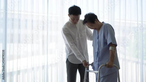 Adult Asian son help mother do physical therapy using walker in hospital love encourage and care family
