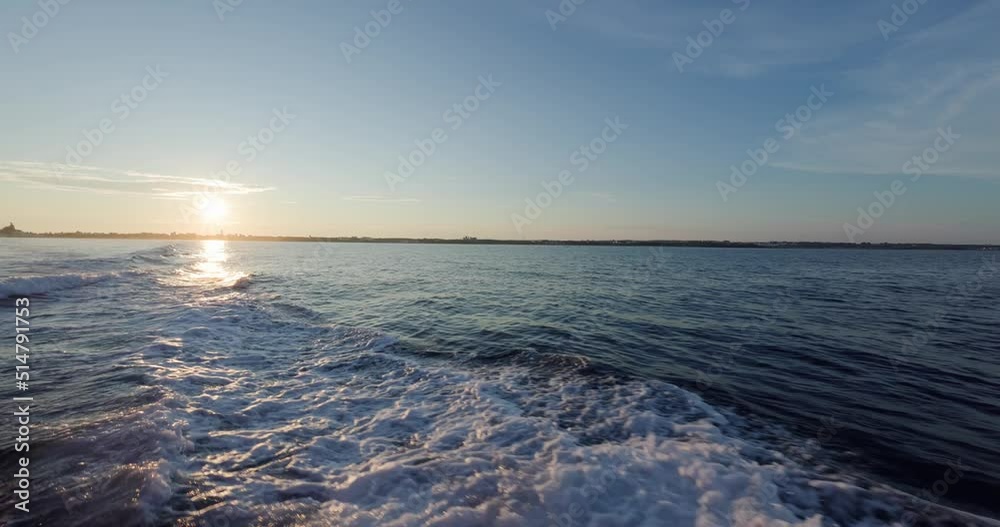Back of the ship cruising over the sea at sunset time