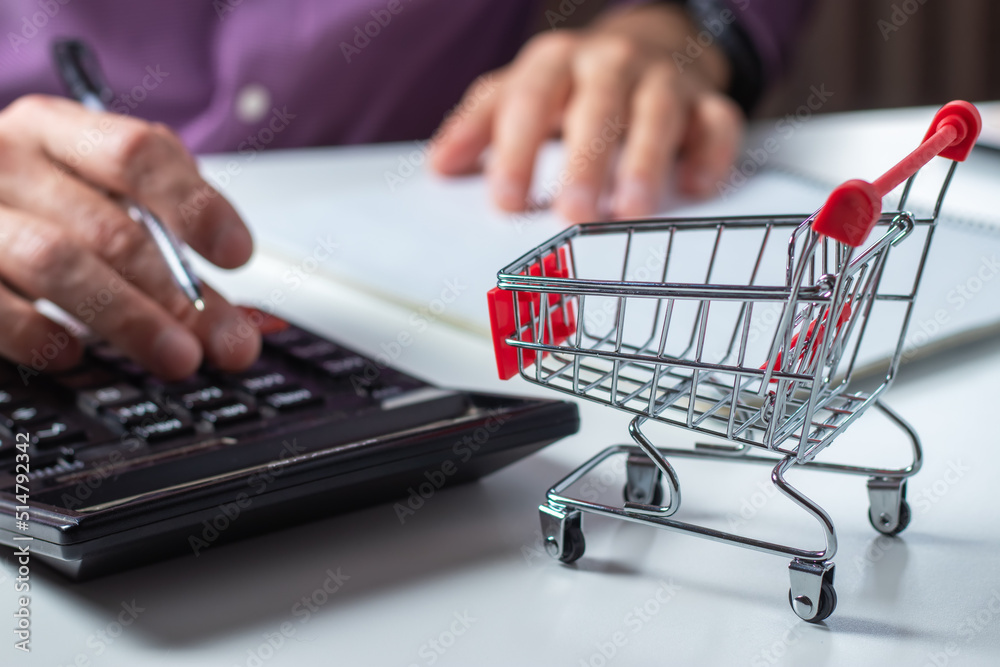 Man calculates the budget. Shopping cart a on table with calculator and paper. Budget of poor and low income family. Man calculates the budget. Shopping cart a on table with calculator and paper. Budget of poor and low income family.