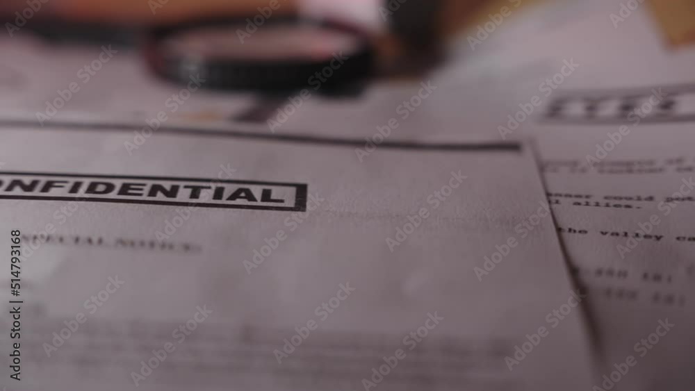 Slow move to reveal confidential stamp on secret document on a desk in