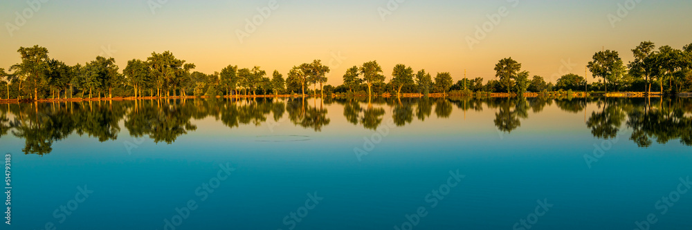 Tranquil water reflections of the cottonwood trees at Deshler Reservoir Park in Ohio Tranquil water reflections of the cottonwood trees at Deshler Reservoir Park in Ohio