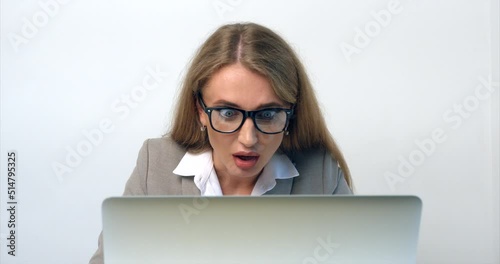 Close-up portrait of the shoked businesswoman with spectacles working on the laptop in the office. White background. photo