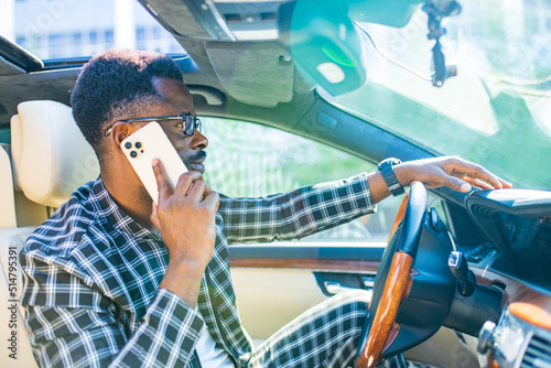 african american businessman making phone call while sitting on seat of a car
