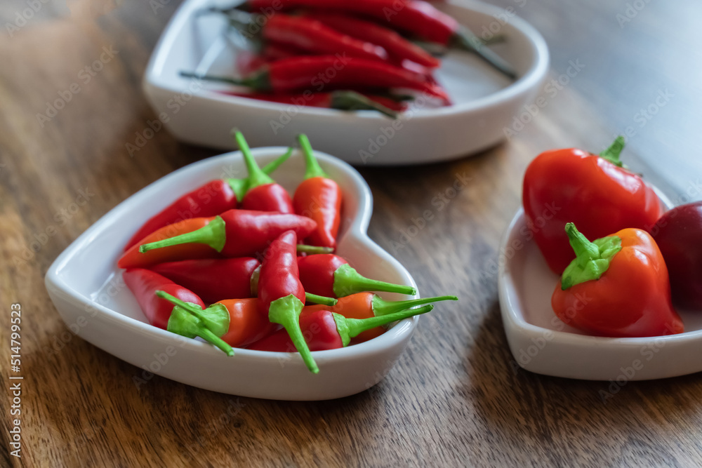 hot assorted red peppers in a white plate on a wooden background selective focus hot assorted red peppers in a white plate on a wooden background selective focus
