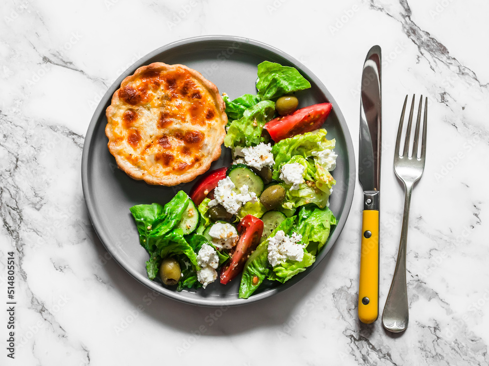 Delicious lunch - mini canned tuna, mozzarella quiche and Greek salad on a light background, top view