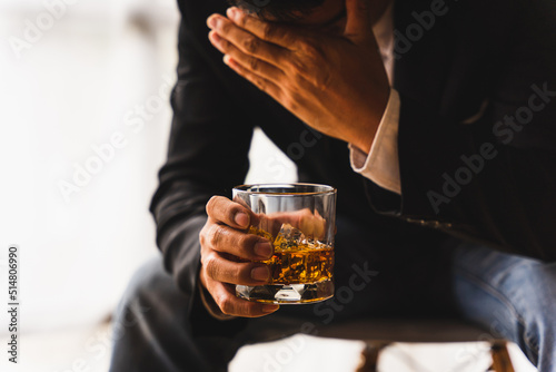 Alcoholism, depressed asian young man sleep on table while drinking alcoholic beverage, holding glass of whiskey alone at night. Treatment of alcohol addiction, suffer abuse problem alcoholism concept photo