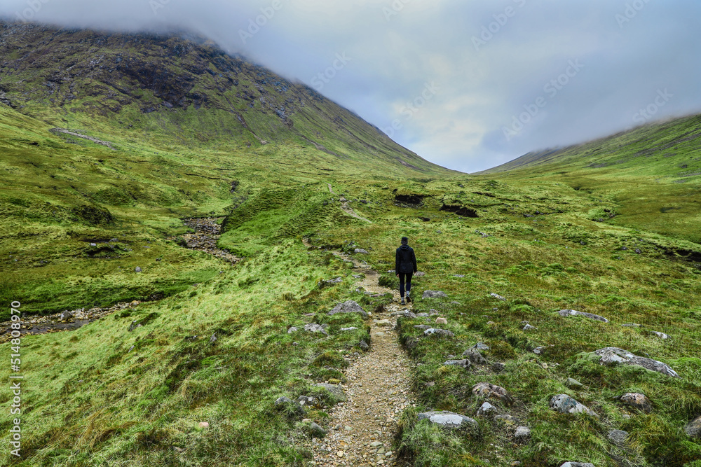 Hiker on in the dramatic green valley of Buachaille Etive Beag in the Scottish Highlands