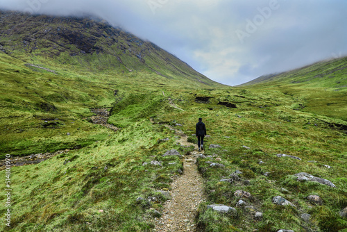 Hiker on in the dramatic green valley of Buachaille Etive Beag in the Scottish Highlands