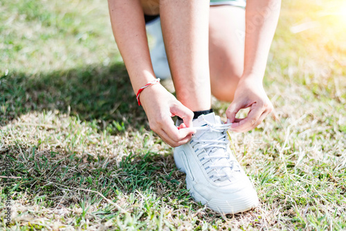 Female hands tying shoelace on running shoes before practice. Woman athlete preparing for jogging outdoors. Runner getting ready for training. Sport active lifestyle concept. Close-up