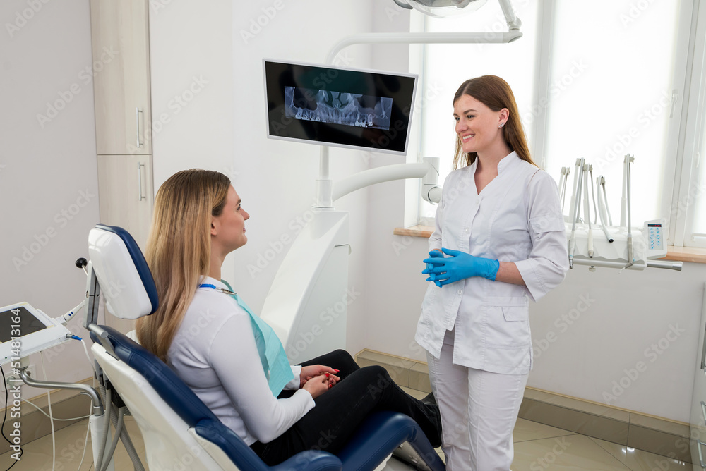 She is sitting in the dentist's chair. The dentist explains and advises the patient. She is sitting in the dentist's chair. The dentist explains and advises the patient.