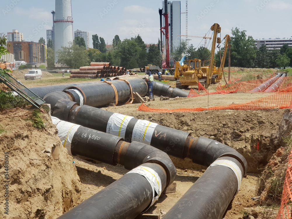 Laying heating pipes in a trench at construction site.