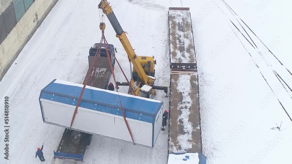 A crane lifts a cargo container onto a railway platform to send goods to a customer, winter concept, import and export concepts, top view, loading work.