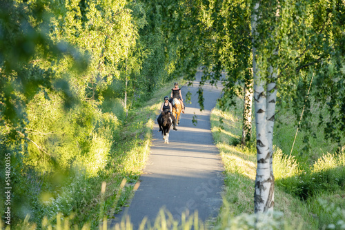 Two riders on the road on summer evening during sunset. Black helmets.