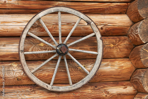 An old wooden cart wheel as an element of modern decor. Copy space. © ROMAN DZIUBALO