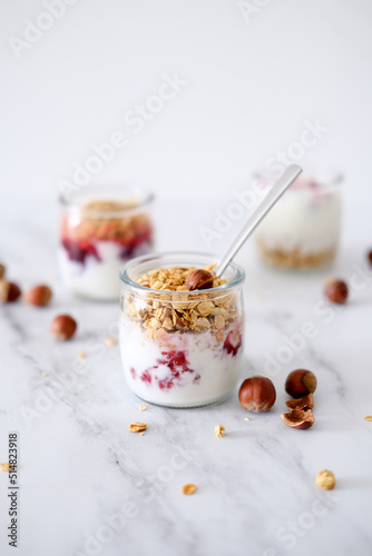 Oatmeal Granola with greek yogurt and nuts strawberry muesli in jars on light background