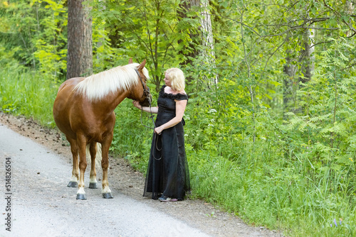 Woman posing with estonian horse in summer evening.