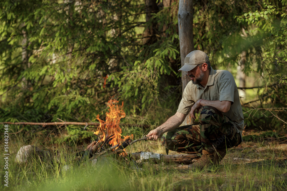 Man in military clothes is making campfire in the woods. The concept of adventure, travel, tourism, camping, survival and evacuation. Man in military clothes is making campfire in the woods. The concept of adventure, travel, tourism, camping, survival and evacuation.