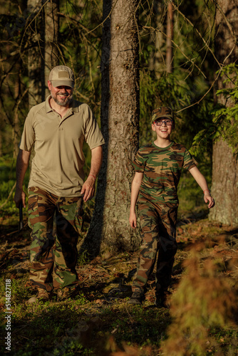 Father and son in military clothes spending time together in the woods. The concept of adventure, travel, tourism and camping