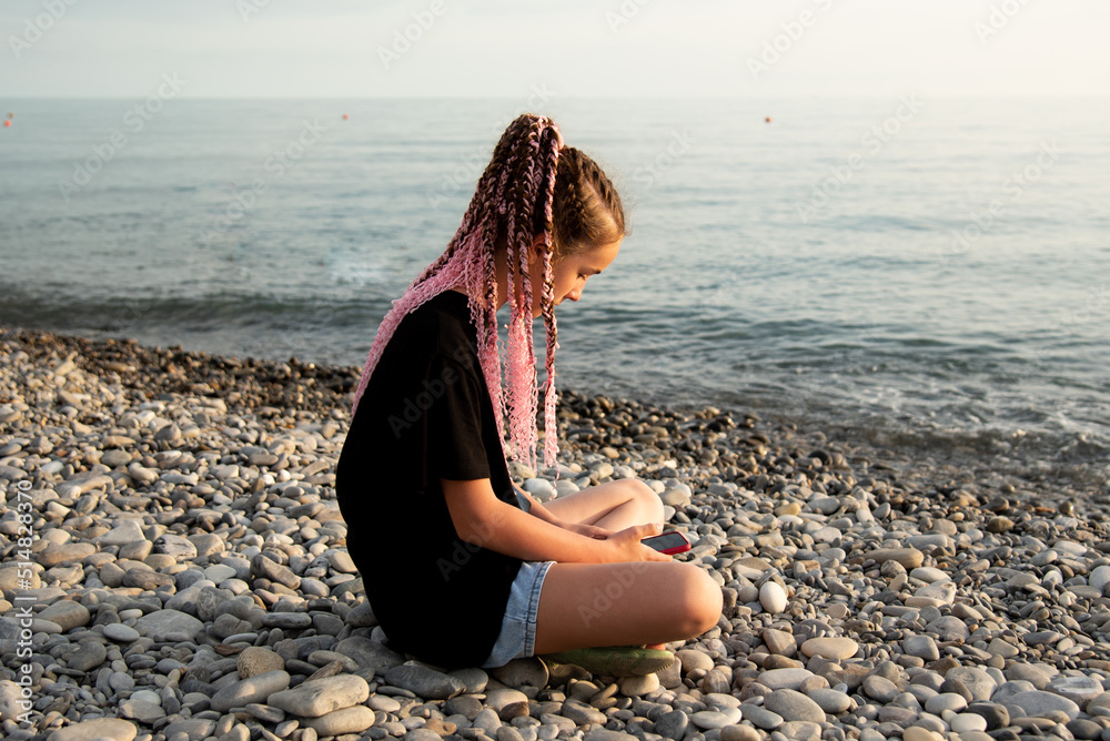 The girl sits and communicates online. Communication. Generation Z. Recreation. Sea.