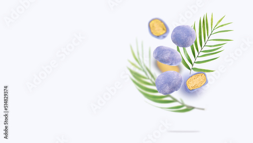 Japanese rice cakes float in the air. A conceptual composition of flying mochi and green palm leaves on a blue background. Asian cuisine, sweet street food desserts. Concept creative food. Copy spase