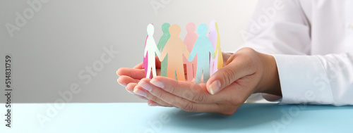 Woman holding paper human figures at table, closeup. Diversity and Inclusion concept
