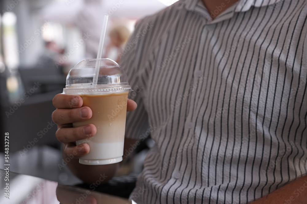 Man with plastic takeaway cup of delicious iced coffee in outdoor cafe, closeup Man with plastic takeaway cup of delicious iced coffee in outdoor cafe, closeup