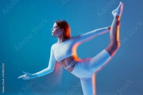 Slim flexible girl stretching body with raised leg. Ballet workout. Fitness, pilates, gymnastics training. Long exposure photo