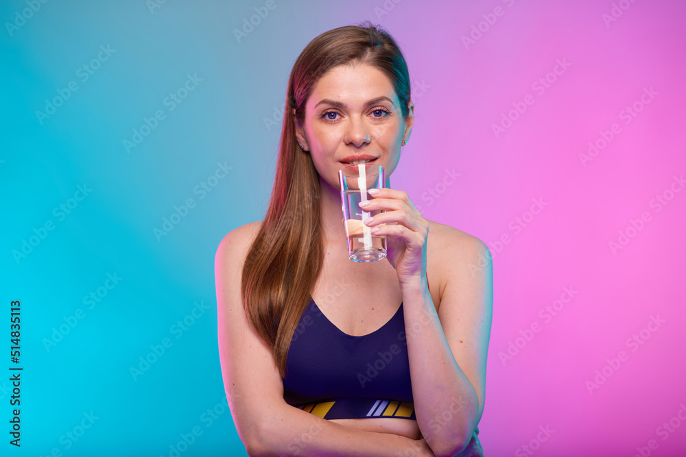 Smiling sporty woman in sportswear drinking water. Female fitness portrait isolated on neon multicolor background. Smiling sporty woman in sportswear drinking water. Female fitness portrait isolated on neon multicolor background.