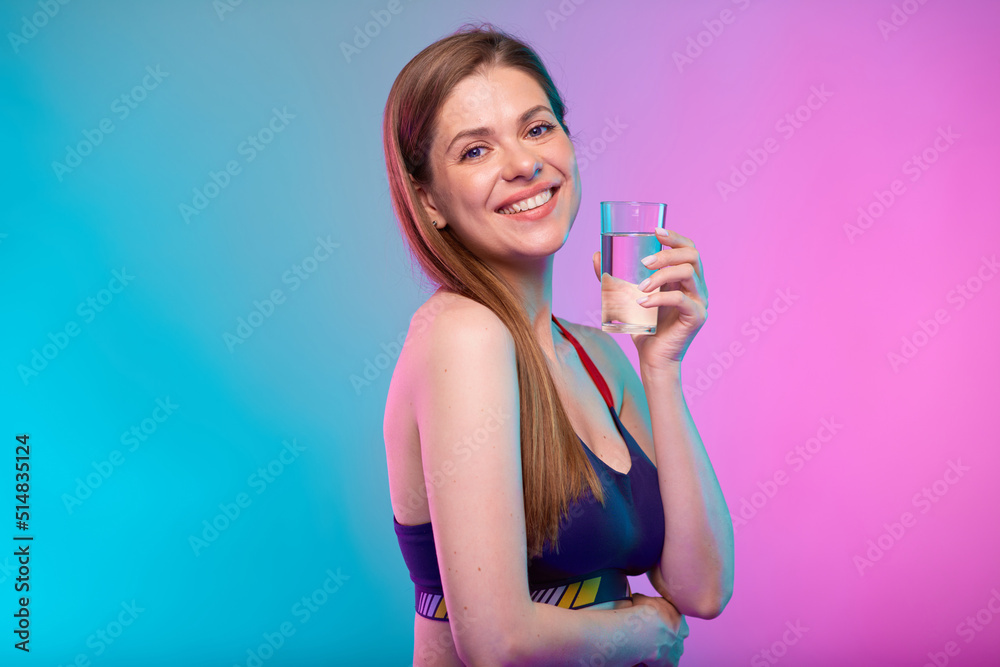Happy young woman in sportswear with water glass. Female fitness portrait isolated on neon pink and azure color background. Happy young woman in sportswear with water glass. Female fitness portrait isolated on neon pink and azure color background.