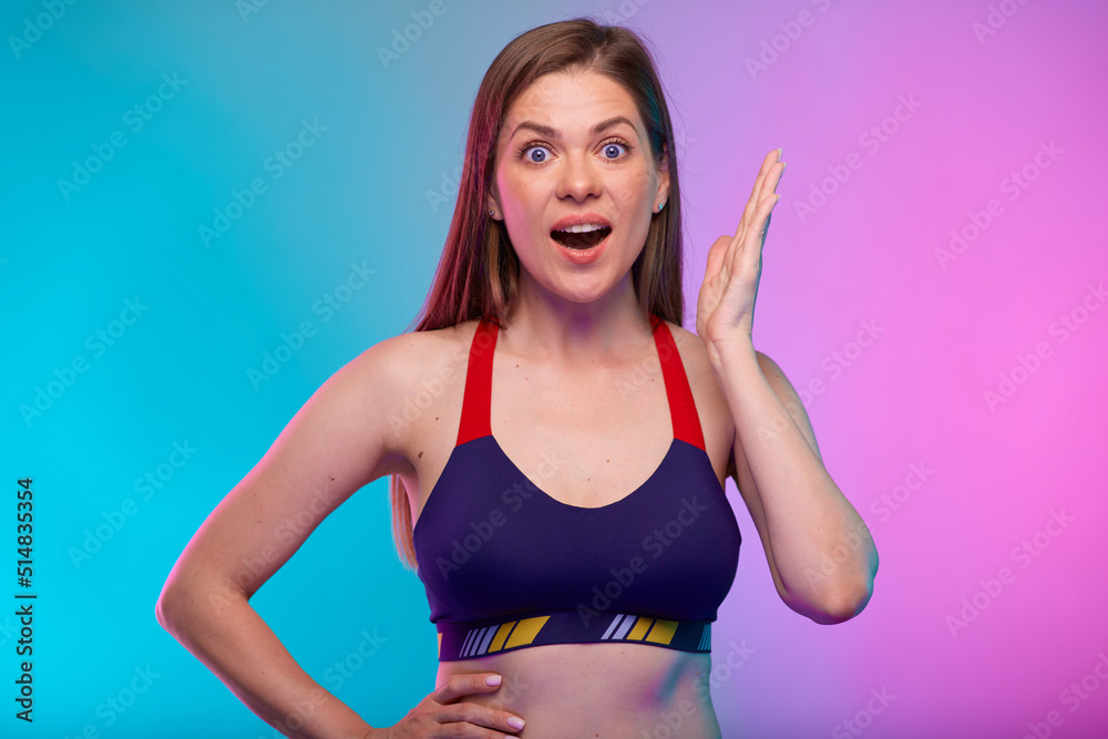 Amazed sporty woman in fitness sportswear holding hands up. Female fitness portrait isolated on neon multicolor background. Amazed sporty woman in fitness sportswear holding hands up. Female fitness portrait isolated on neon multicolor background.