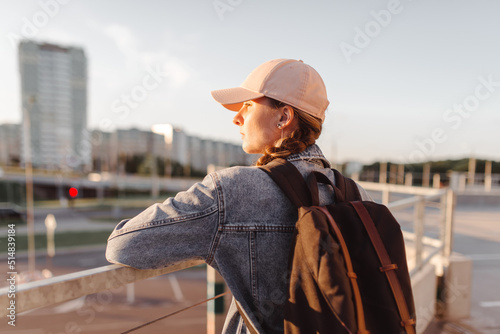 Tourist girl with her backpack at sunset looking at city landscape, back view Adventure and travel in the concept . Backpack rear view. Tourism in city. © prochkailo