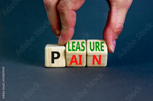 Pain or pleasure symbol. Concept words Pain or Pleasure on wooden cubes. Businessman hand. Beautiful grey table grey background. Business and pain or pleasure concept. Copy space.
