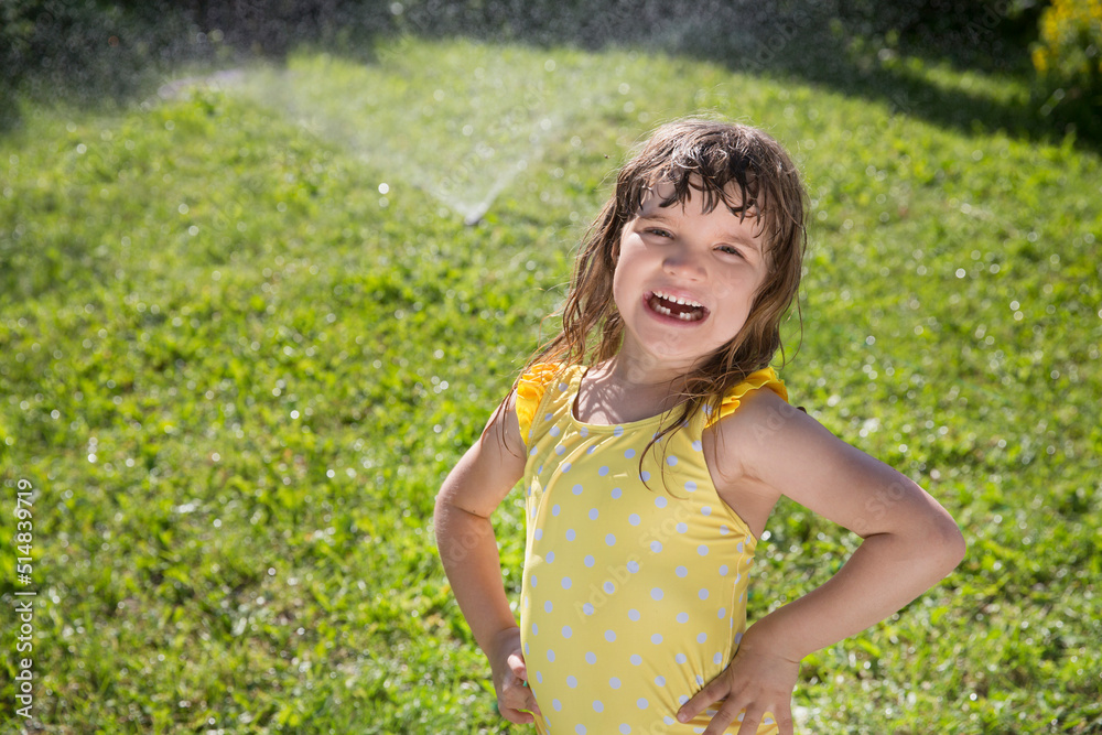 Happy child girl playing with garden hose and having fun with spray of water in sunny backyard. Summer time. Kid Boy helps water garden with hose. Slow life. Enjoying the little things. Summer holiday Happy child girl playing with garden hose and having fun with spray of water in sunny backyard. Summer time. Kid Boy helps water garden with hose. Slow life. Enjoying the little things. Summer holiday