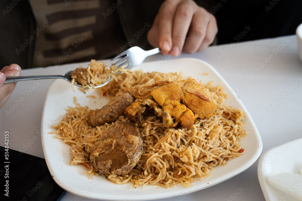eating Pakistani traditional chicken pulao kabab with fork and spoon