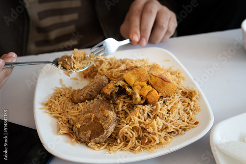 eating Pakistani traditional chicken pulao kabab with fork and spoon