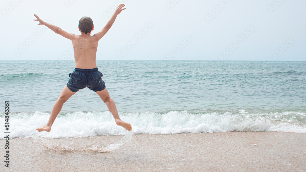 Boy from behind jumping for joy and from behind looking at the beach Boy from behind jumping for joy and from behind looking at the beach