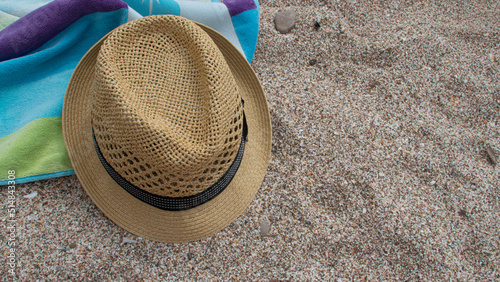 Yellow straw hat towel shade of blue and green colors on white sand