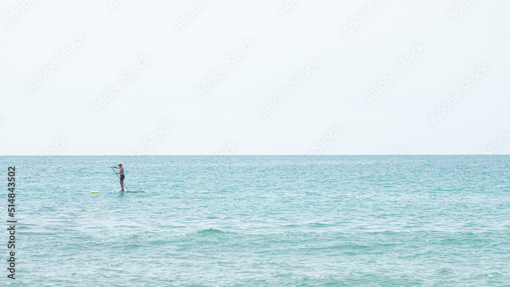 Silhouette of a man kayaking in the distance on the waters of the Mediterranean Sea