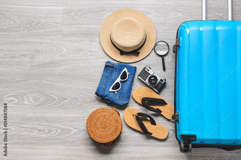 Suitcase and different accessories for travelling on grey wooden background Suitcase and different accessories for travelling on grey wooden background