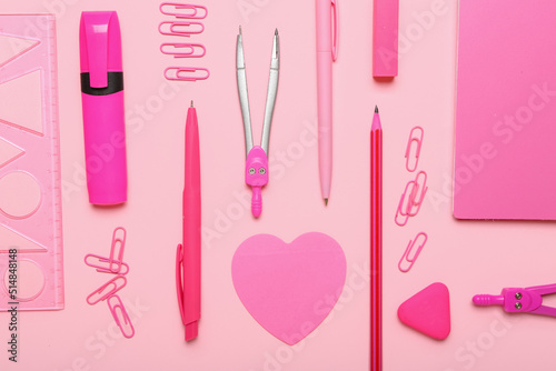 Pink paper clips and school stationery on color background
