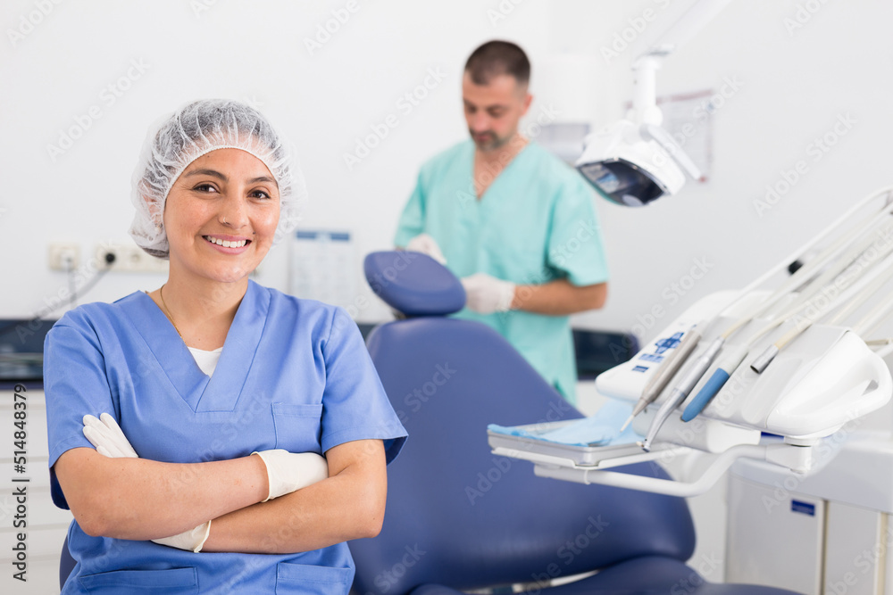 Portrait of woman nurse in uniform with crossed hands at her workplace in dental clinic office