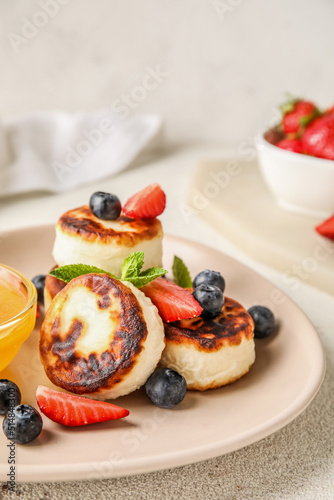 Delicious cottage cheese pancakes with berries and mint leaves served on white table, closeup
